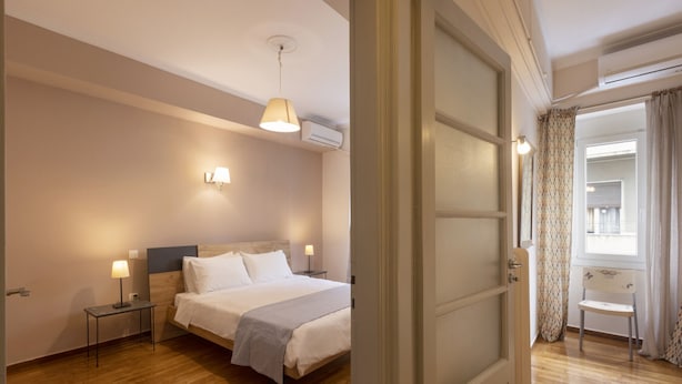 Een hotelkamer met een bed, bedlampjes, een klein tafeltje en een stoel.