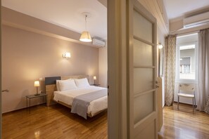 A hotel room with a bed, bedside lamps, a small table, and a chair. - Tzireon 16 · Prime Location 2 BR APT next to the A (Athens)
