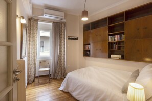 Une chambre à coucher comprenant un lit, une chaise, une bibliothèque et un appareil de climatisation.
