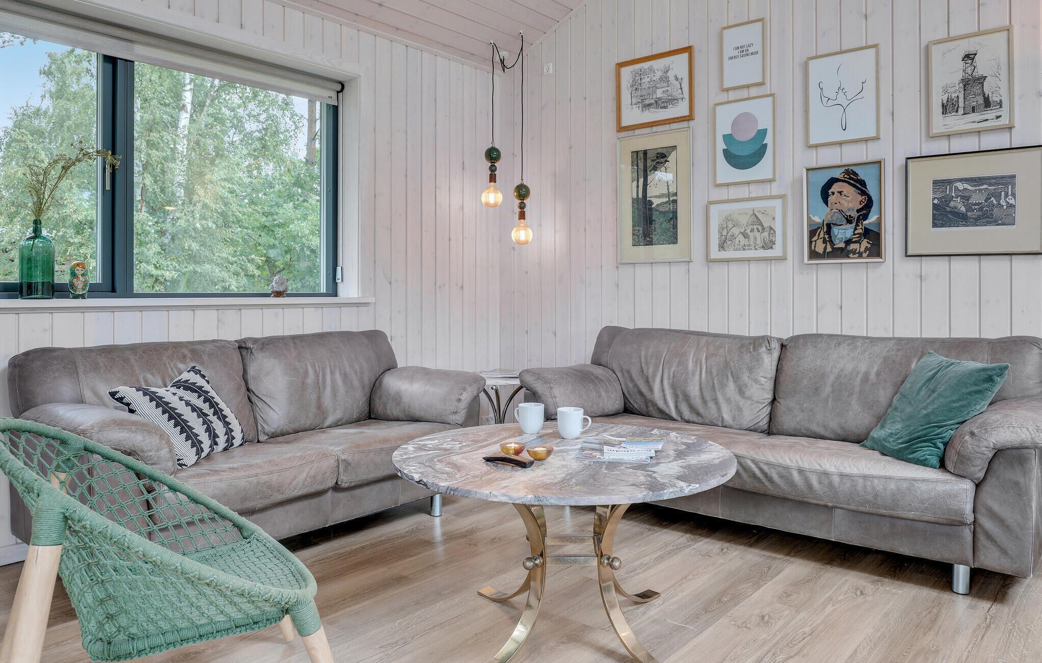 Una sala de estar acogedora con un sofá de cuero gris, una mesa redonda de centro y una silla verde de fibra.