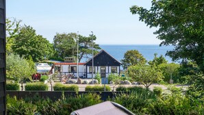 A coastal house with a view of the sea, a small dock with a boat, and a garden area. - Stunning home in Allinge (Allinge)