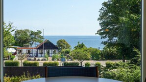 A view from a window overlooking a coastal area with a building, a road, and a body of water. - Stunning home in Allinge (Allinge)