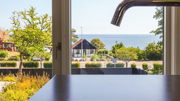 A view from a window overlooking a coastal area with a house, greenery, and the sea. - Stunning home in Allinge (Allinge)