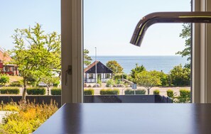 A view from a window overlooking a coastal area with a house, greenery, and the sea. - Stunning home in Allinge (Allinge)