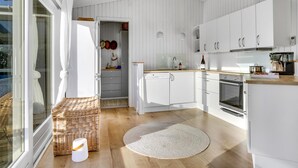 Ett modernt kök med vita skåp, en inbyggd ugn och en kaffemaskin.