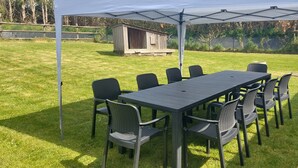 An outdoor patio with a table and chairs under a white canopy.