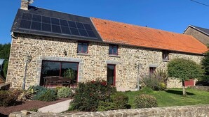 A stone house with a tiled roof, a chimney, and a solar panel.