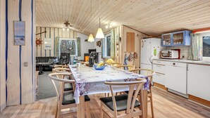 Kodikas keittiö, jossa on ruokapöytä, tuoleja ja jääkaappi.