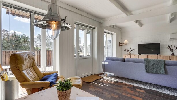 Una sala de estar con un sofá, una silla, una mesa con una planta y un televisor sobre un mueble de madera.