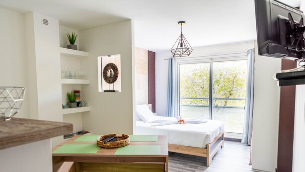 Una habitación moderna con cama, zona de comedor y televisor.