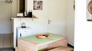 Una cocina moderna con una mesa de madera, un refrigerador pequeño y una lámpara colgante.