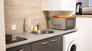 Cocina compacta con microondas integrado, lavabo y lavadora.