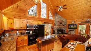 Un'ampia baita di legno con cucina, zona pranzo e soggiorno. Dispone di pavimenti in legno, un camino in pietra e un'ampia finestra.