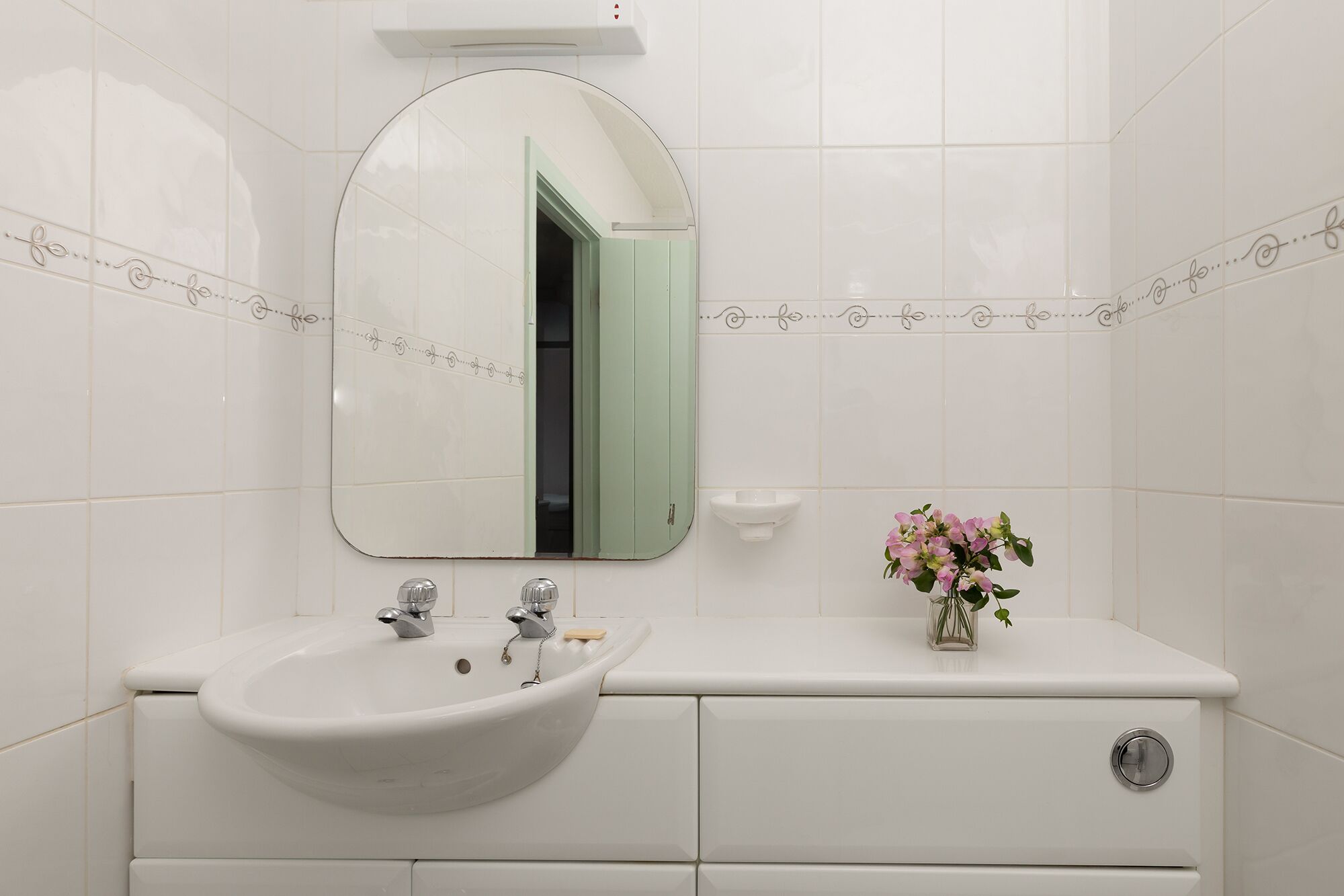 Un bany amb un lavabo blanc, un armari verd i un mirall.