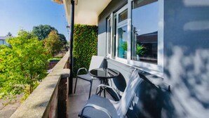 A balcony with two chairs and a small table, overlooking a garden with green foliage and a brick wall. - Beautiful 1-bed Apartment in York Near Gym (York)