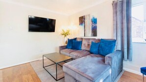 A modern living room with a sectional sofa, a coffee table, a flat-screen TV, and a painting on the wall. - Beautiful 1-bed Apartment in York Near Gym (York)