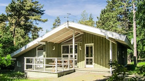 Eine Holzhütte mit geneigtem Dach, großen Fenstern und einer Terrassenfläche.
