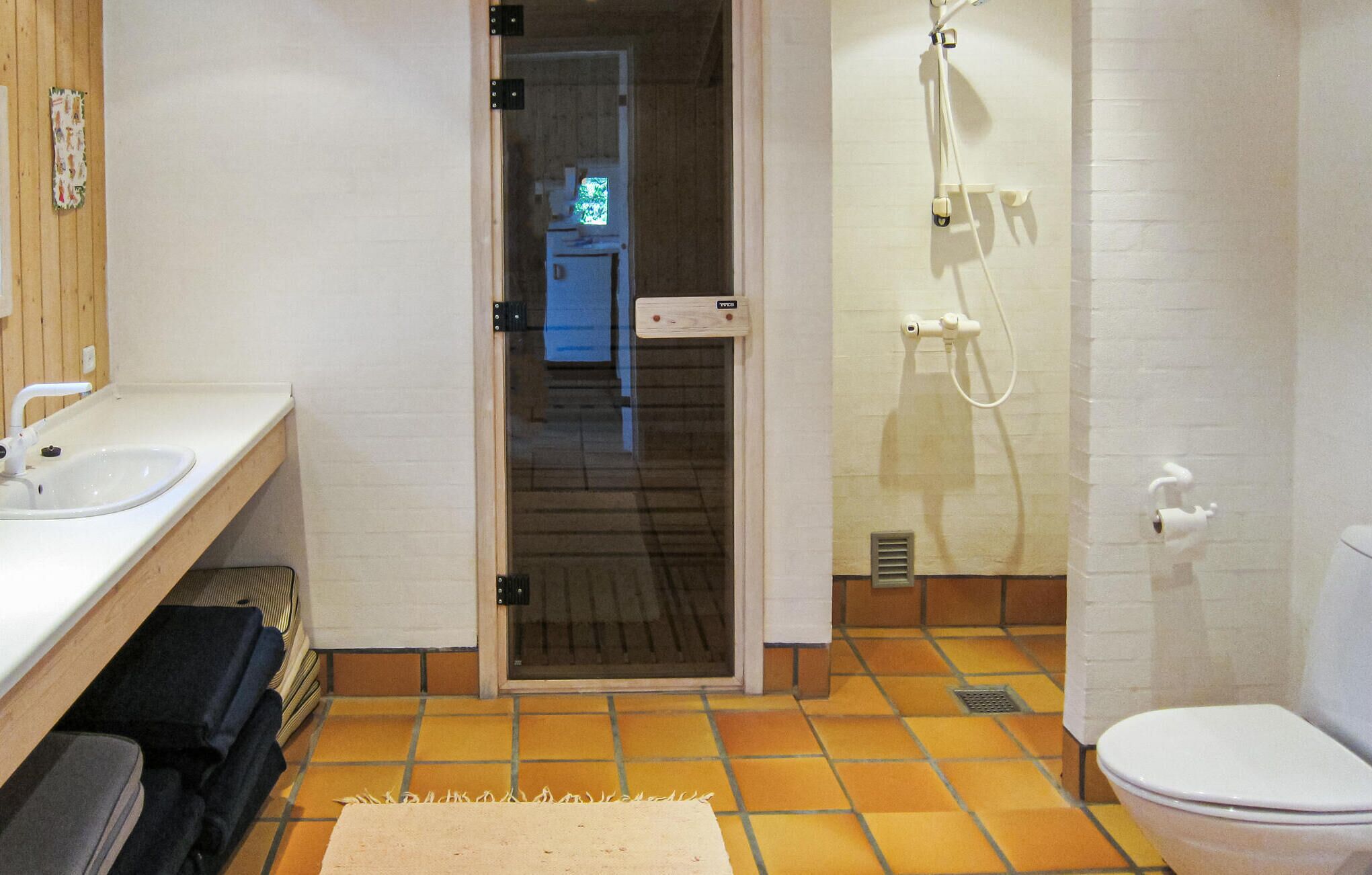 Et badeværelse med en hvid vask, toilet og bruser.
