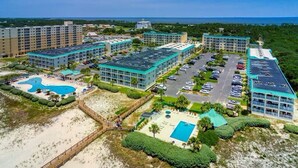 Un resort con varias edificaciones, una piscina grande y una zona de playa.