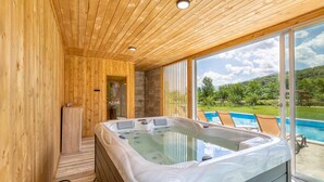 Uma cabana de madeira com hidromassagem e vista para uma piscina.