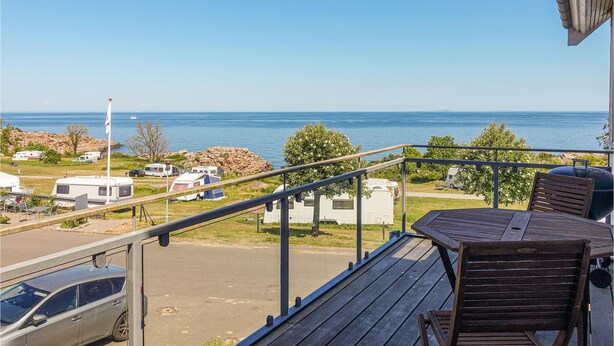 Ein Balkon mit Meerblick, einem Grill und Wohnmobilen im Hintergrund.