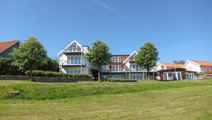 Ein mehrstöckiges Wohnhaus mit Balkon, umgeben von einer Rasenfläche und Bäumen.