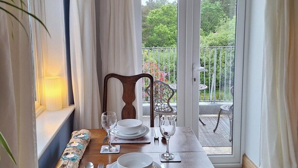 Mesa de comedor para cuatro personas con vistas a un balcón y jardín.