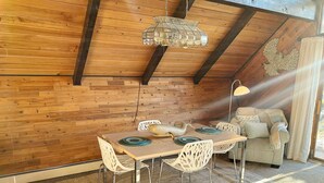 A cozy dining area with a wooden ceiling, a chandelier, and a table set for two. - Bel-Hygge 🐋Chalet, cozy comfort the AK way (Anchorage)