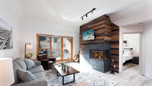 A modern living room with a fireplace, a sofa, a coffee table, and a large window.