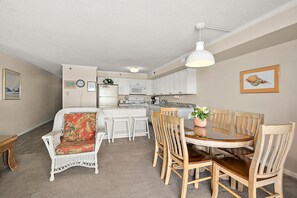 A compact kitchen with white cabinets, a microwave, and a refrigerator. There is a dining area with a round table and wooden chairs. - 2 br 2 bath, ocean and boardwalk front at 3rd St / large balcony (Ocean City)
