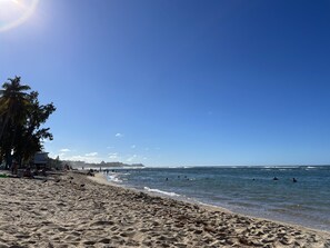 A sandy beach with palm trees and a clear blue sky.