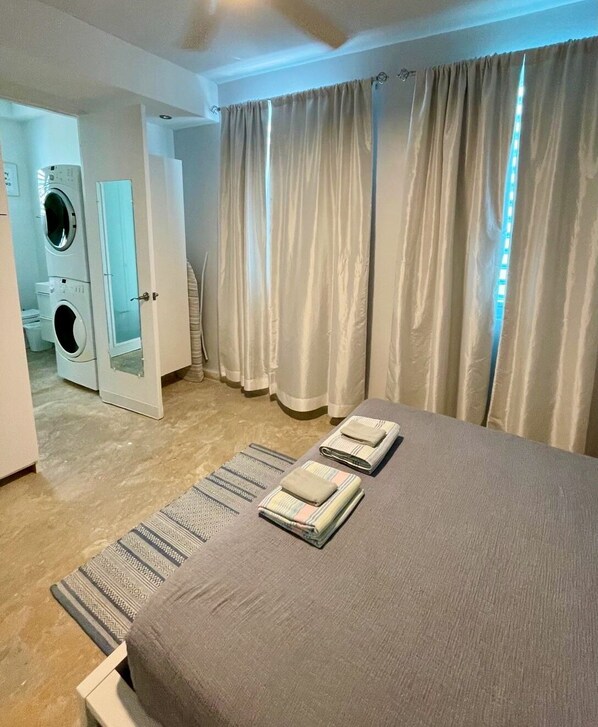 A hotel room with a bed, a washing machine, and a bathroom. - 5 min walk to a beautiful beach and a big shady park! 28min walk to Old San Juan (San Juan)