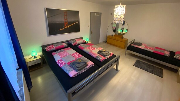 A bedroom with a bed, a dresser, a mirror, and a painting of the Golden Gate Bridge.