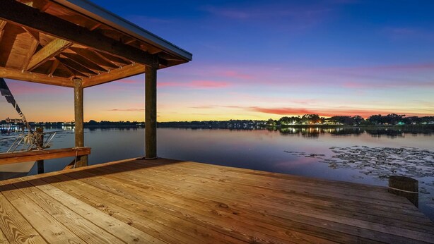 A wooden dock extending over calm water with a sunset in the background.