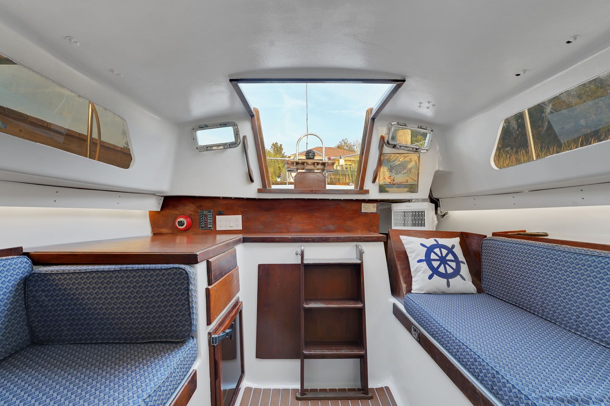 A boat interior with a central seating area, a small table, and a window providing a view of the outside.