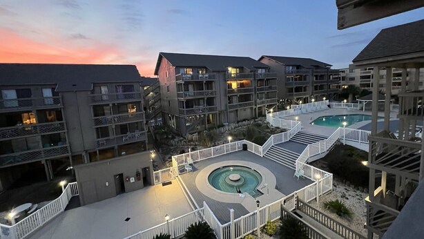 A resort with multiple swimming pools, a central fountain, and a well-lit outdoor area.