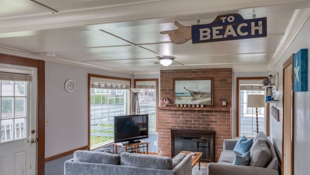 A living room with a television, a fireplace, and a sign that reads "TO BEACH". - Perfect Beach Cottage, Friendly, Walk to Beach and Seaside Promenade (Seaside)