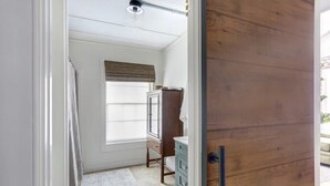 A room with a wooden door, a window with blinds, a dresser, and a rug. - Cozy Modern Studio Just 2 Blocks To Forsyth Park! (Savannah)