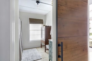 A room with a wooden wardrobe, a dresser, a window with blinds, and a small rug. - Cozy Modern Studio Just 2 Blocks To Forsyth Park! (Savannah)