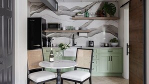 A kitchen with a marble backsplash, a dining table with chairs, and a refrigerator. - Cozy Modern Studio Just 2 Blocks To Forsyth Park! (Savannah)