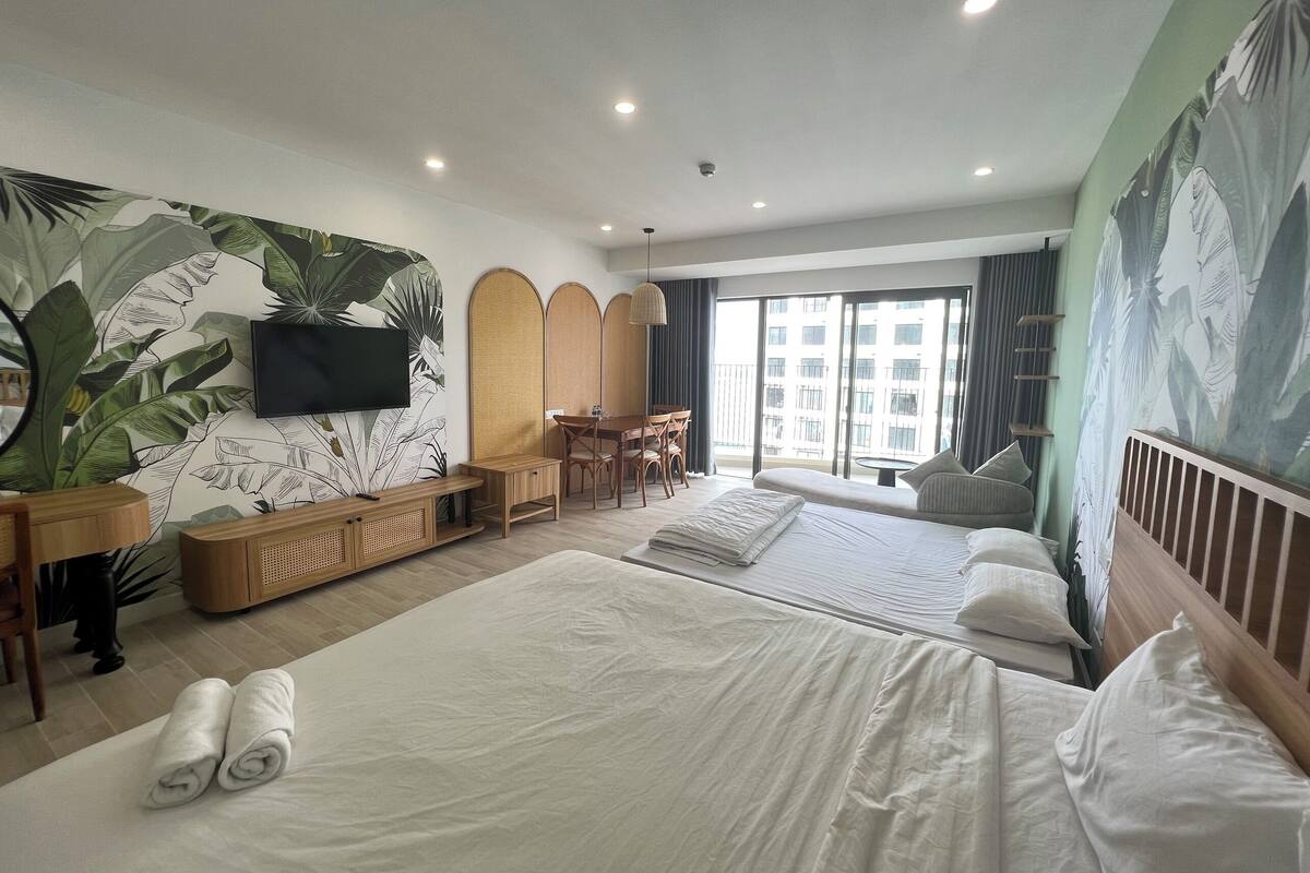 Hotelkamer met een groot bed, een bureau, een stoel, een televisie en een balkon met uitzicht op gebouwen.