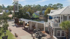 A waterfront property with a covered patio, outdoor seating, and a view of the water. - Charming Coastal 2BR Villa, GOLF CART, Cozy Sunroom, Near Beach, Pool, Wharf. (Miramar Beach)