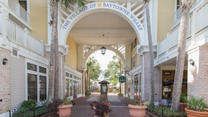 Stroll through the charming entrance of Baytowne Wharf, surrounded by historic buildings with large windows and balconies.