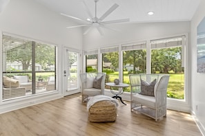 Relax in this serene room with a high ceiling, ceiling fan, and expansive garden views.