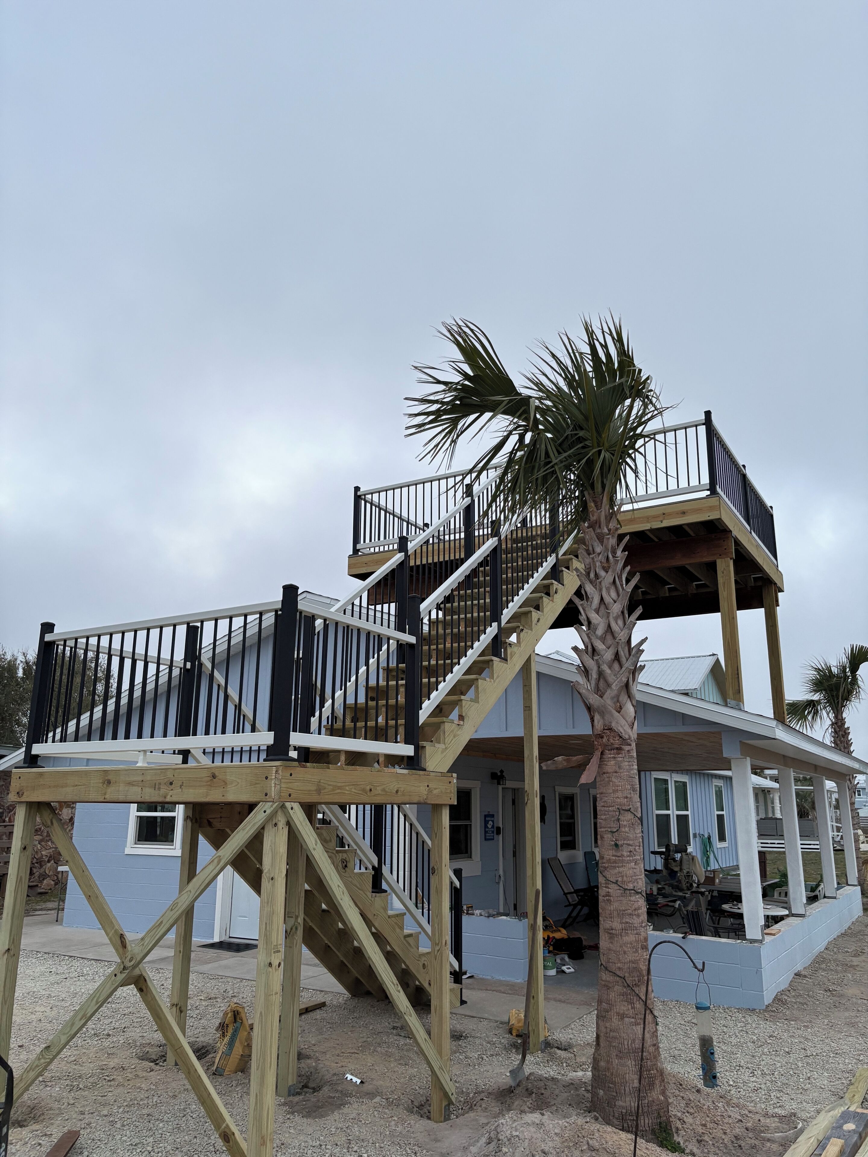 Une maison à deux étages avec une terrasse en bois et un escalier.