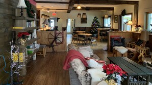 Um interior acolhedor e rústico, com vigas de madeira, área de jantar, árvore de Natal e lareira.