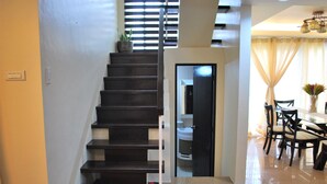 A staircase leading to a second floor, a dining area with chairs and a table, and a door to a bathroom.