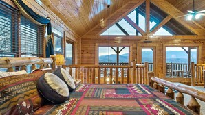 Ein Blockhauszimmer mit einem großen Bett, Bergblick und einem Holzbalkon.