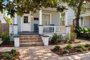 A two-story house with a front porch, a mailbox, and a street sign.