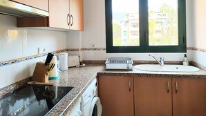 A kitchen with a stove, oven, microwave, and a window with a view of buildings. - Holiday Apartment - Javea Puerto - 2bedr 2 Bath (Javea)